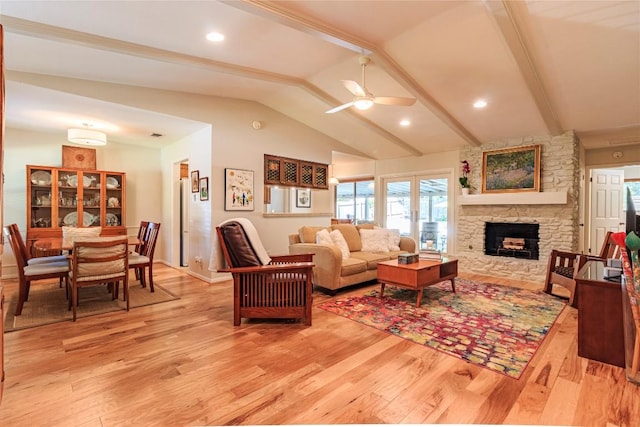 living room with lofted ceiling, a stone fireplace, light hardwood / wood-style flooring, and ceiling fan