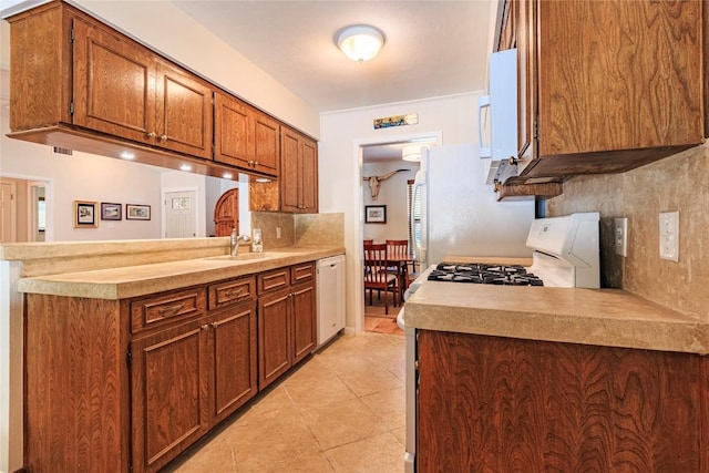 kitchen featuring sink, white appliances, kitchen peninsula, and decorative backsplash