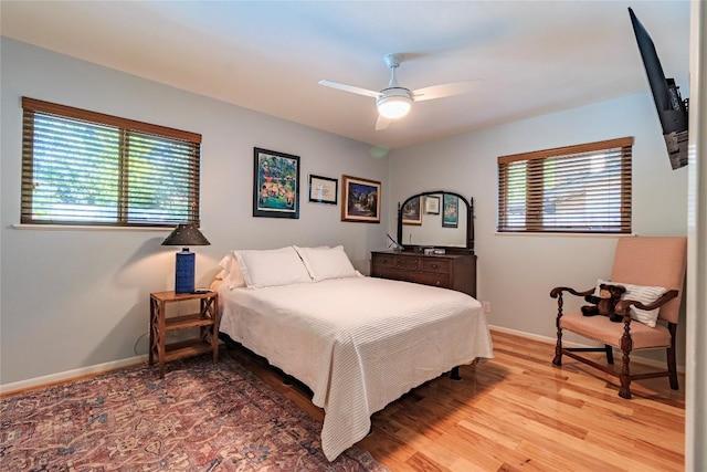 bedroom featuring ceiling fan, wood-type flooring, and multiple windows