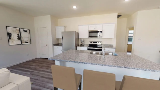 kitchen featuring sink, a breakfast bar, appliances with stainless steel finishes, white cabinetry, and light stone countertops