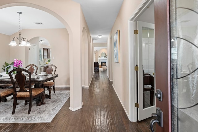 corridor with dark hardwood / wood-style floors and a notable chandelier