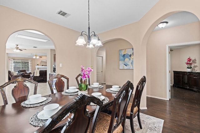 dining space with ceiling fan with notable chandelier and dark hardwood / wood-style flooring