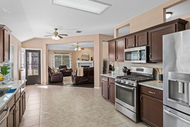 kitchen featuring light stone counters, a fireplace, dark brown cabinets, and stainless steel appliances