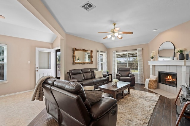 living room with a tile fireplace, lofted ceiling, and ceiling fan