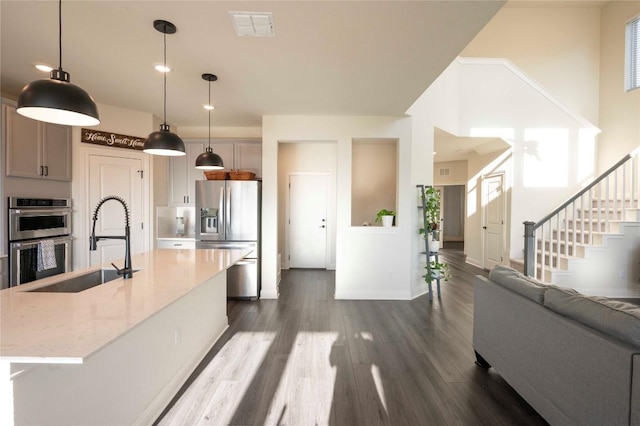 kitchen featuring gray cabinets, light stone countertops, appliances with stainless steel finishes, and decorative light fixtures