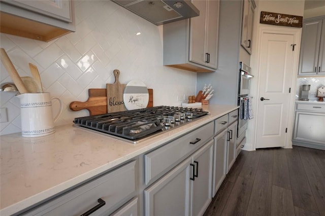 kitchen featuring dark wood-type flooring, gray cabinets, stainless steel appliances, tasteful backsplash, and exhaust hood