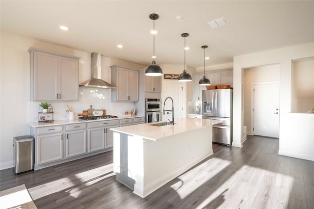 kitchen with pendant lighting, wall chimney range hood, stainless steel appliances, and gray cabinetry