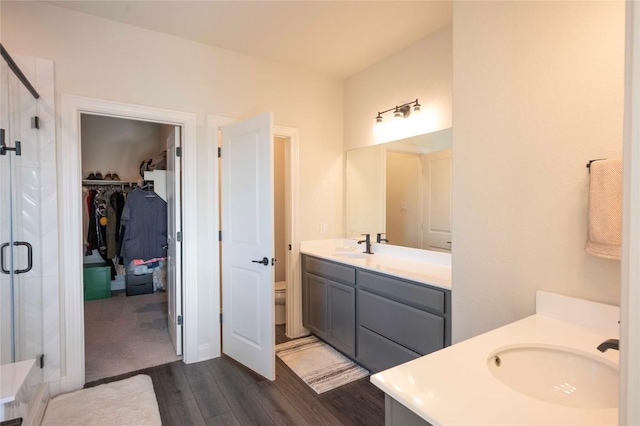 bathroom featuring hardwood / wood-style flooring, vanity, a shower with shower door, and toilet