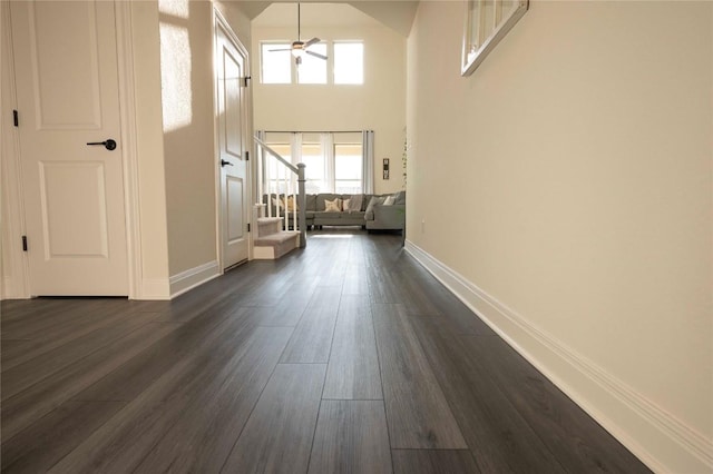 interior space with dark wood-type flooring and a towering ceiling