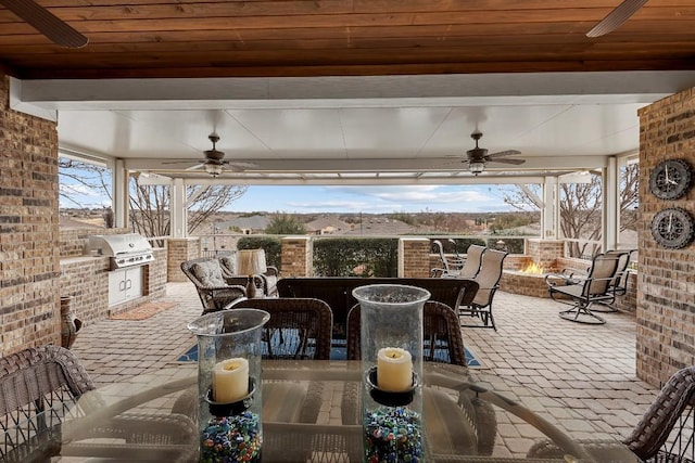 view of patio / terrace featuring area for grilling, an outdoor bar, ceiling fan, exterior kitchen, and a fire pit