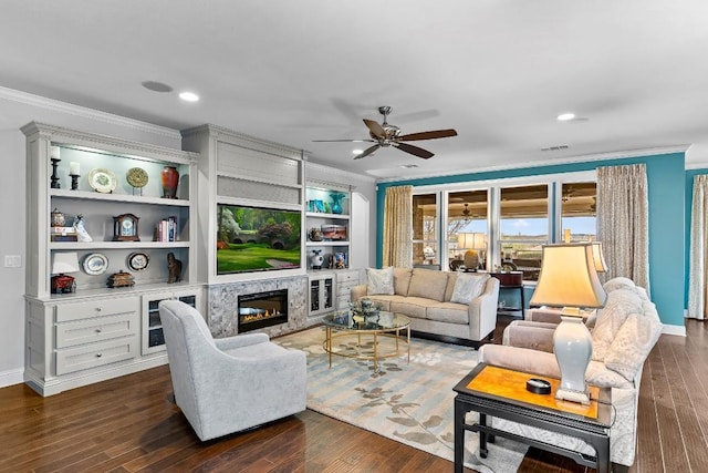 living room featuring dark hardwood / wood-style flooring, ornamental molding, a premium fireplace, and ceiling fan