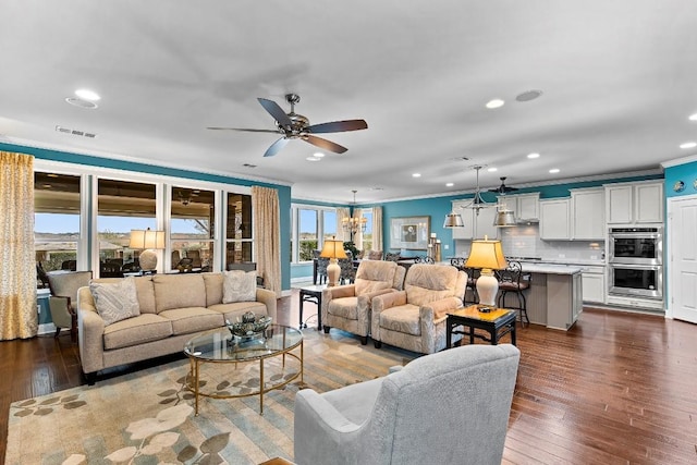 living room featuring crown molding, dark wood-type flooring, and ceiling fan with notable chandelier