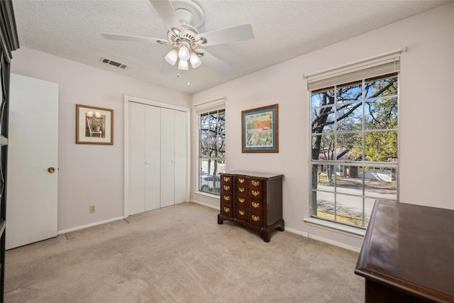 carpeted bedroom featuring ceiling fan, a closet, and a textured ceiling