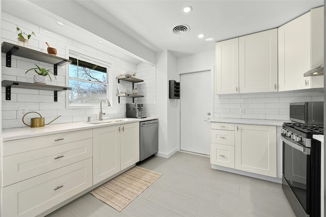 1801 Duke Ave, Austin, TX 78757 - kitchen with stainless steel appliances, a sink, open shelves, decorative backsplash, and light countertops