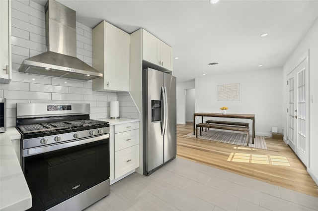 1801 Duke Ave, Austin, TX 78757 - kitchen featuring stainless steel appliances, wall chimney range hood, light countertops, backsplash, and white cabinetry