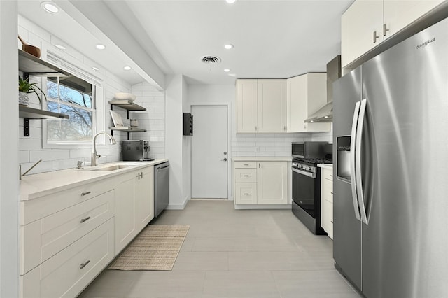 1801 Duke Ave, Austin, TX 78757 - kitchen featuring appliances with stainless steel finishes, open shelves, a sink, wall chimney exhaust hood, and backsplash