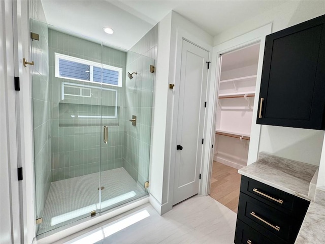 1708 Canterbury St Unit 1, Austin, TX 78702 - bathroom with a shower stall, a walk in closet, vanity, recessed lighting, and wood finished floors