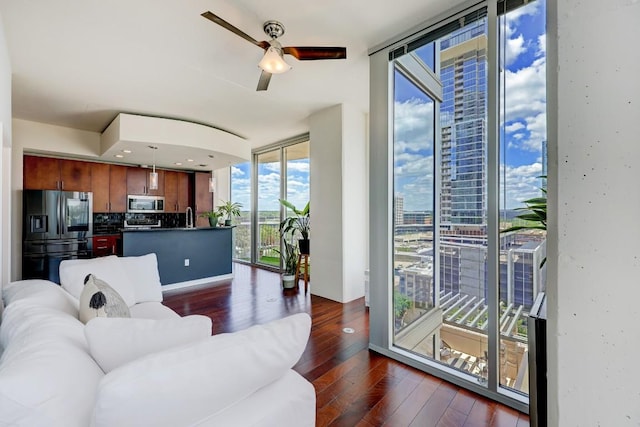 living area with a ceiling fan, dark wood-style flooring, and expansive windows