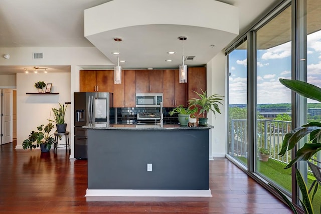 kitchen with brown cabinetry, visible vents, dark wood-style flooring, appliances with stainless steel finishes, and backsplash