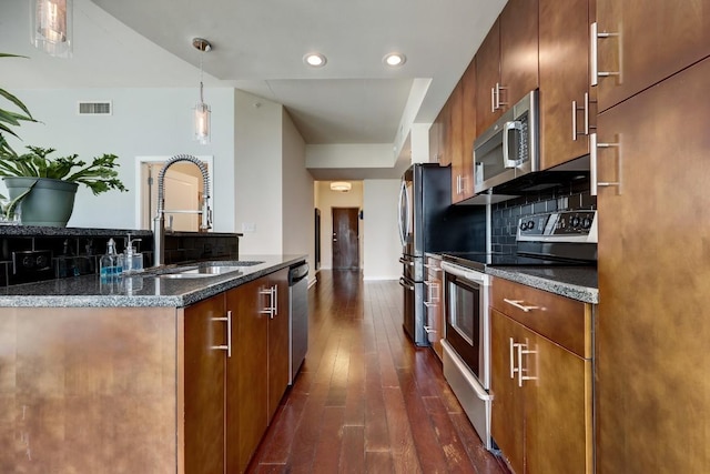 kitchen featuring visible vents, dark wood-type flooring, a sink, appliances with stainless steel finishes, and backsplash