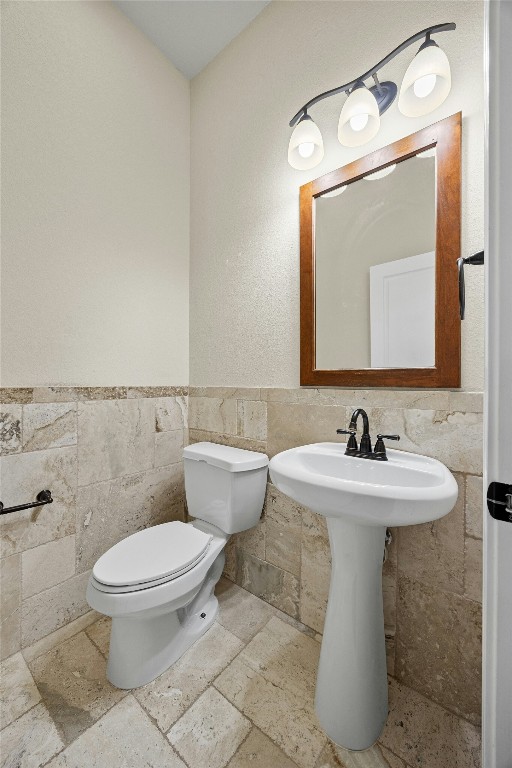 bathroom featuring toilet and tile walls