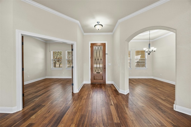 foyer with dark wood-type flooring, crown molding, and a chandelier