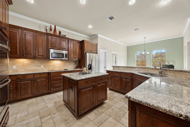 kitchen featuring sink, appliances with stainless steel finishes, hanging light fixtures, a center island, and light stone countertops