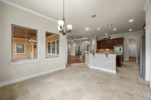 kitchen with a kitchen bar, ornamental molding, hanging light fixtures, and appliances with stainless steel finishes