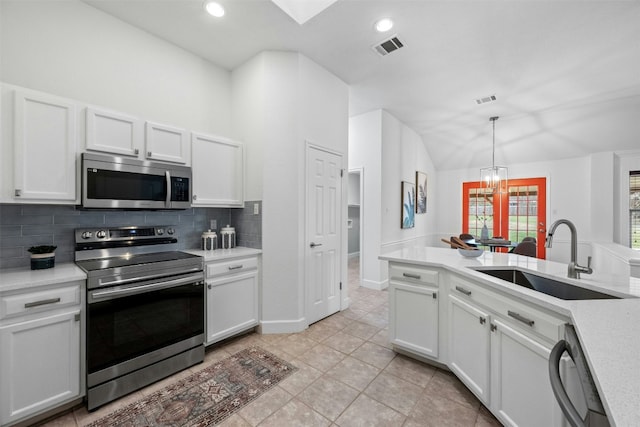 kitchen featuring pendant lighting, sink, white cabinets, decorative backsplash, and stainless steel appliances