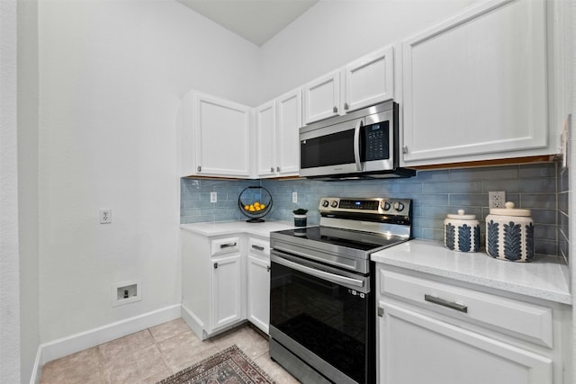 kitchen featuring tasteful backsplash, white cabinetry, light tile patterned floors, stainless steel appliances, and light stone countertops