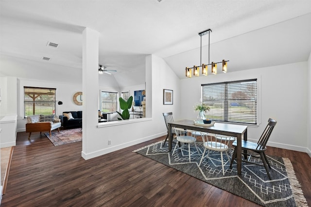 dining area featuring dark hardwood / wood-style flooring, ceiling fan with notable chandelier, and vaulted ceiling