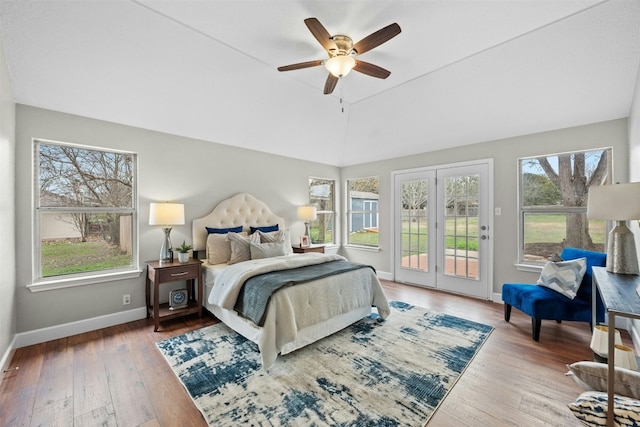 bedroom featuring multiple windows, lofted ceiling, hardwood / wood-style floors, and access to exterior