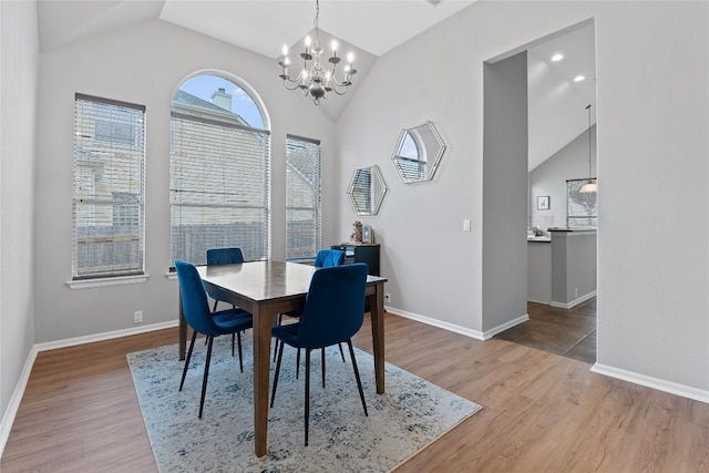 dining space with wood-type flooring, vaulted ceiling, and an inviting chandelier