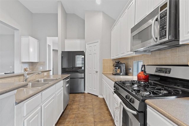 kitchen featuring sink, light tile patterned floors, appliances with stainless steel finishes, white cabinets, and decorative backsplash