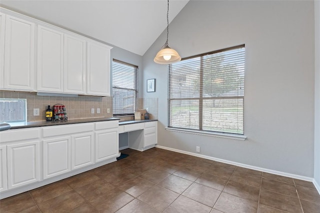 kitchen with pendant lighting, dark tile patterned floors, backsplash, high vaulted ceiling, and white cabinets