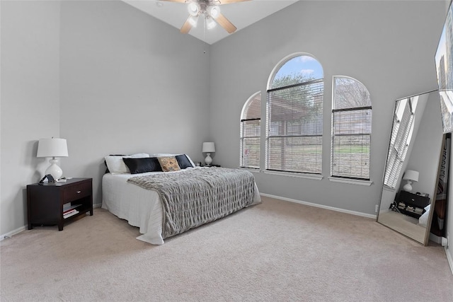 bedroom with ceiling fan, a towering ceiling, and light carpet