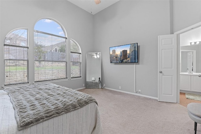 bedroom with light colored carpet, ceiling fan, and a high ceiling