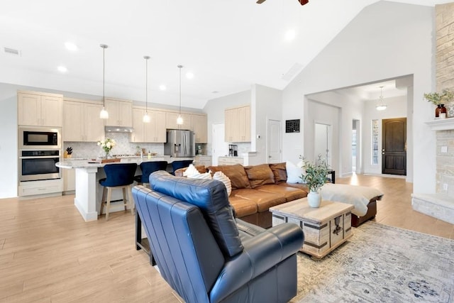 living room featuring ceiling fan, high vaulted ceiling, and light wood-type flooring