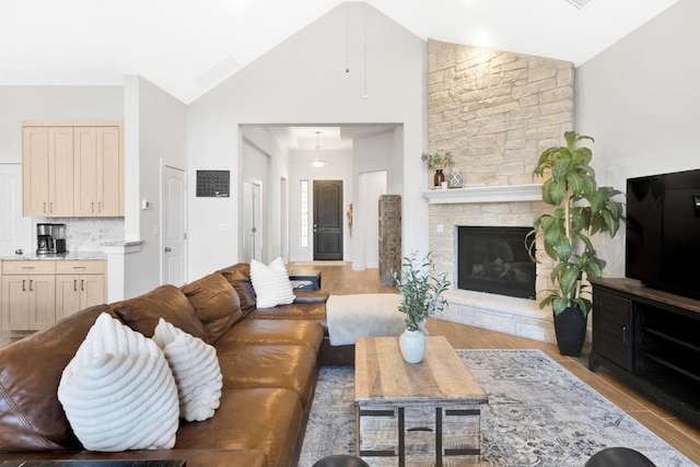 living room featuring a stone fireplace, high vaulted ceiling, and light wood-type flooring