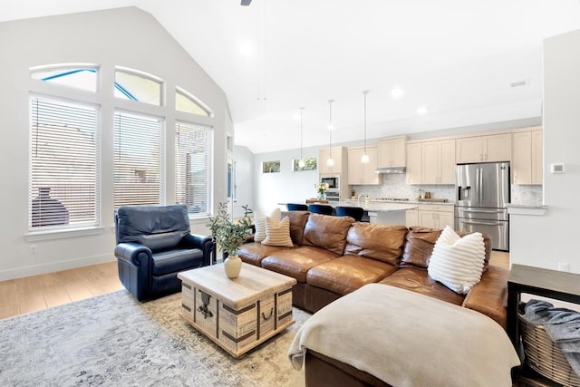 living room featuring high vaulted ceiling and light hardwood / wood-style flooring