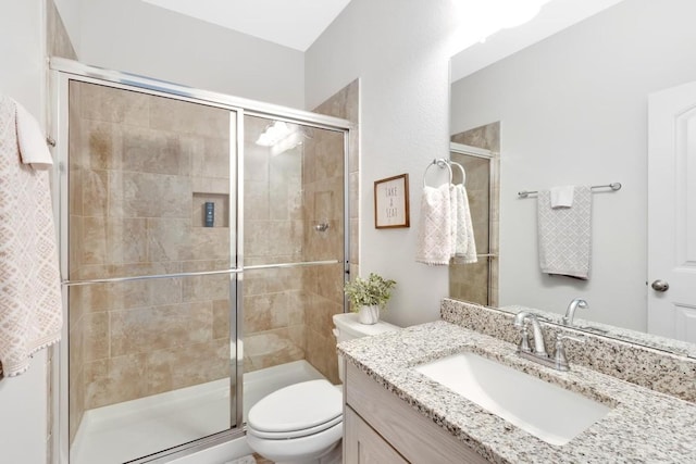 bathroom with walk in shower, vanity, and toilet