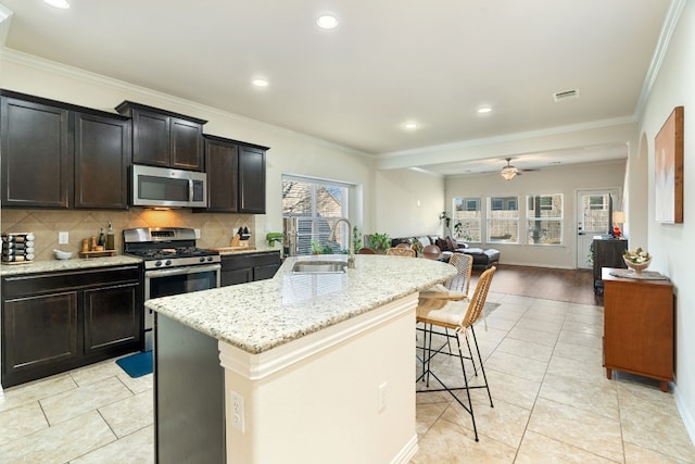 kitchen featuring sink, ornamental molding, stainless steel appliances, a kitchen island with sink, and decorative backsplash