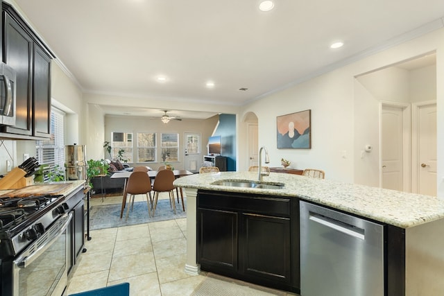 kitchen with sink, light tile patterned floors, stainless steel appliances, light stone counters, and ornamental molding