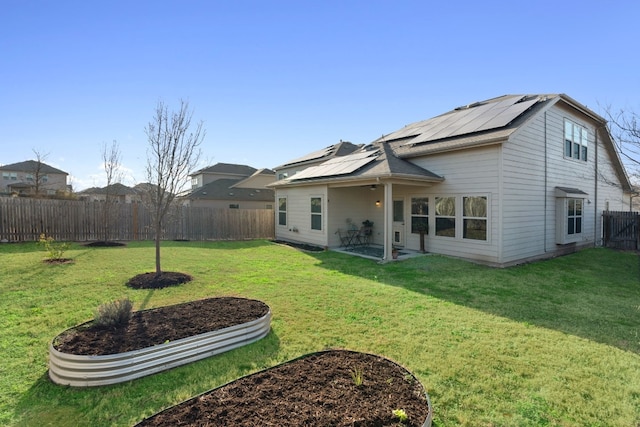 rear view of property featuring a lawn, a patio, and solar panels