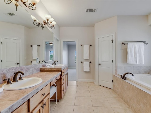 bathroom featuring a notable chandelier, vanity, tiled tub, and tile patterned floors