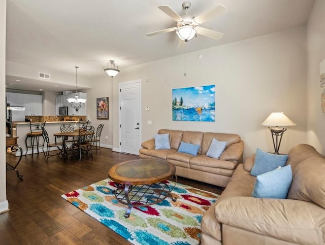 living room featuring dark wood-type flooring and ceiling fan with notable chandelier