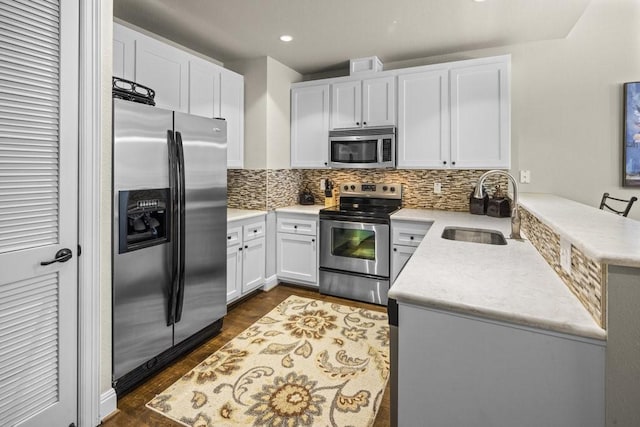 kitchen with sink, white cabinets, dark hardwood / wood-style flooring, backsplash, and stainless steel appliances