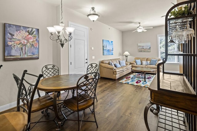 dining space featuring ceiling fan with notable chandelier and dark wood-type flooring