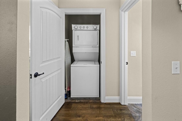 clothes washing area featuring stacked washer and dryer and dark hardwood / wood-style flooring