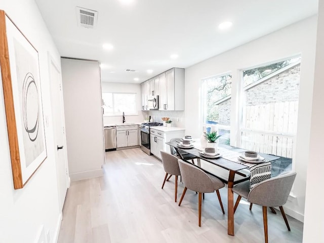 dining area with light hardwood / wood-style floors and sink